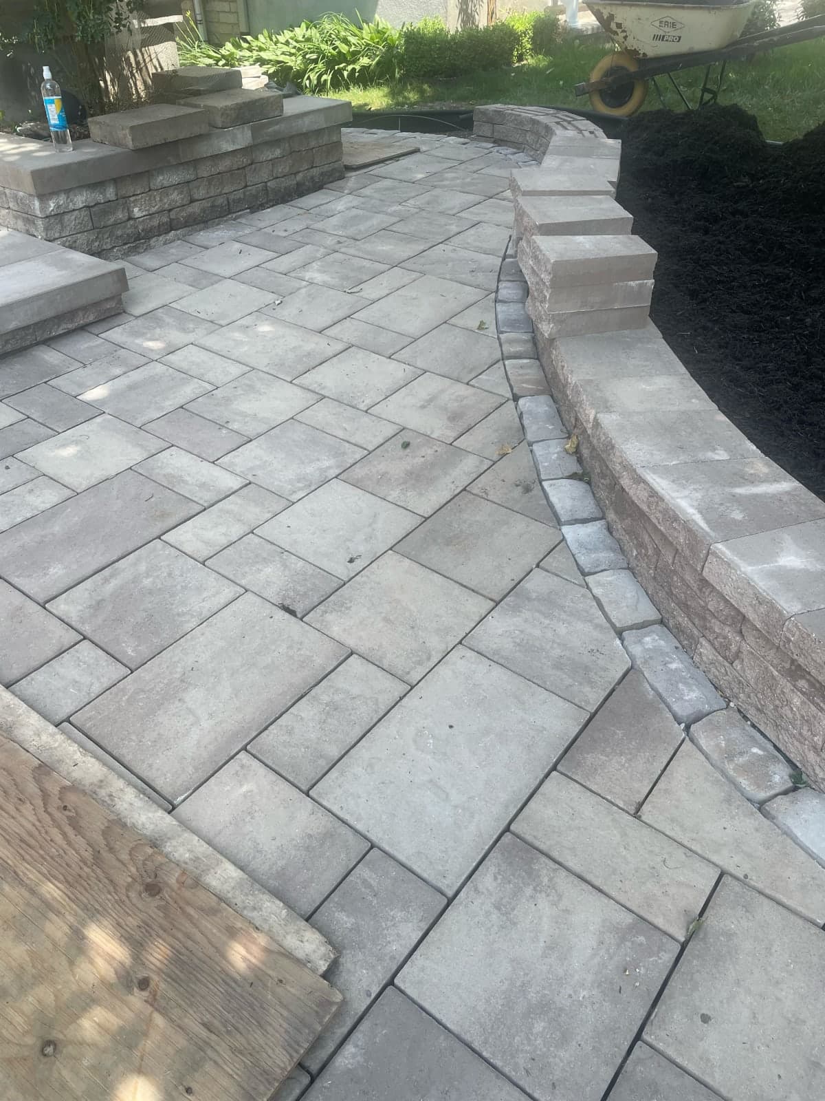Curved backyard patio with natural stone seating wall